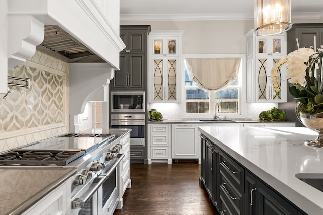kitchen with a sink, glass insert cabinets, white cabinetry, premium range hood, and appliances with stainless steel finishes