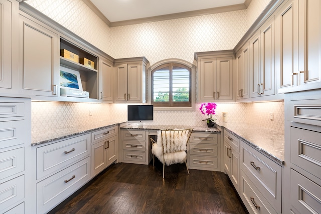 unfurnished office with dark wood-style floors, crown molding, and built in desk