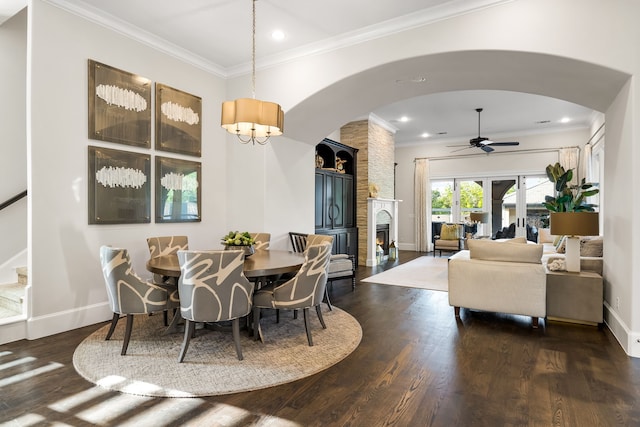 dining area featuring dark wood finished floors, arched walkways, a ceiling fan, and ornamental molding