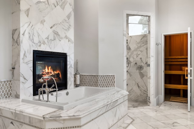 bathroom with a sauna, marble finish floor, a premium fireplace, a marble finish shower, and a garden tub