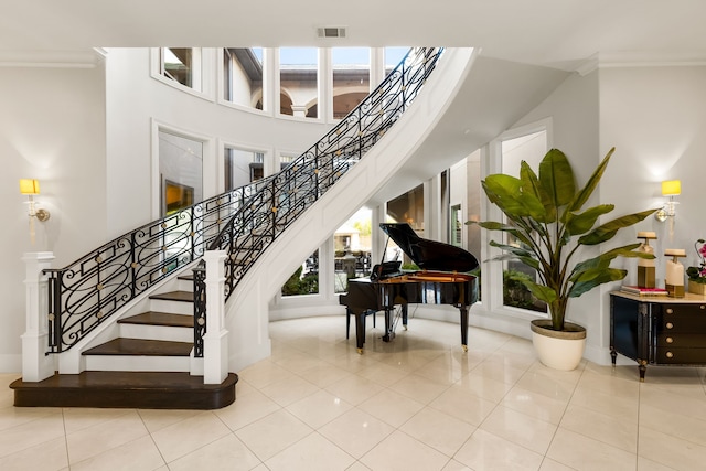 stairway featuring tile patterned floors, visible vents, crown molding, and plenty of natural light