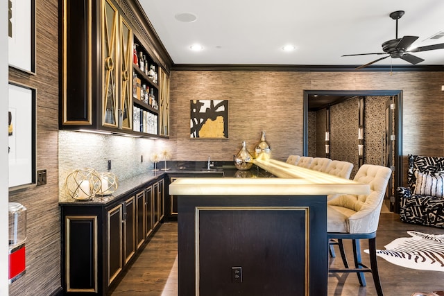 bar featuring recessed lighting, crown molding, indoor wet bar, ceiling fan, and dark wood-type flooring