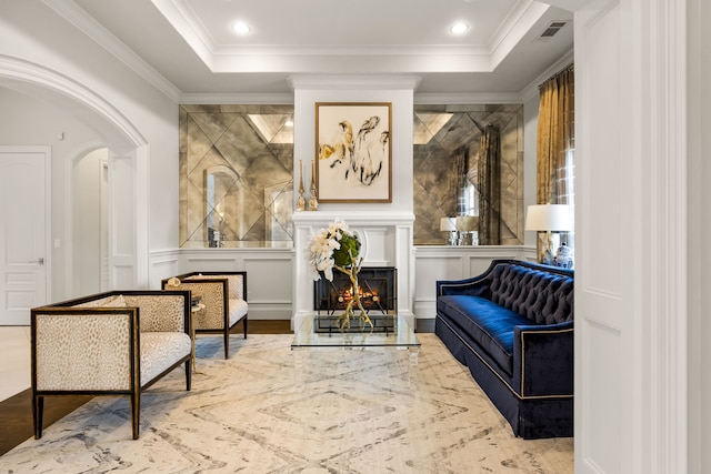 living area with arched walkways, a decorative wall, visible vents, a lit fireplace, and crown molding