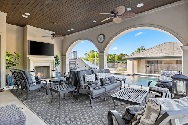 view of patio with fence, an outdoor living space with a fireplace, and a ceiling fan