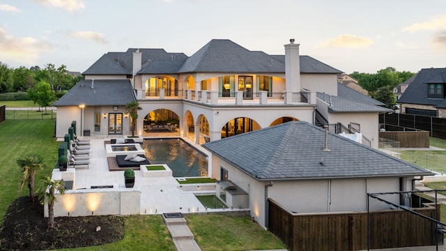 rear view of property with a balcony, a chimney, a patio area, stucco siding, and a fenced backyard