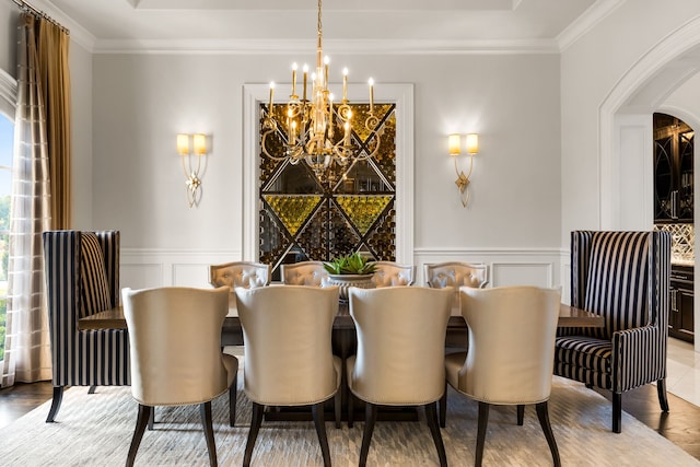 dining room with a decorative wall, arched walkways, an inviting chandelier, and a raised ceiling