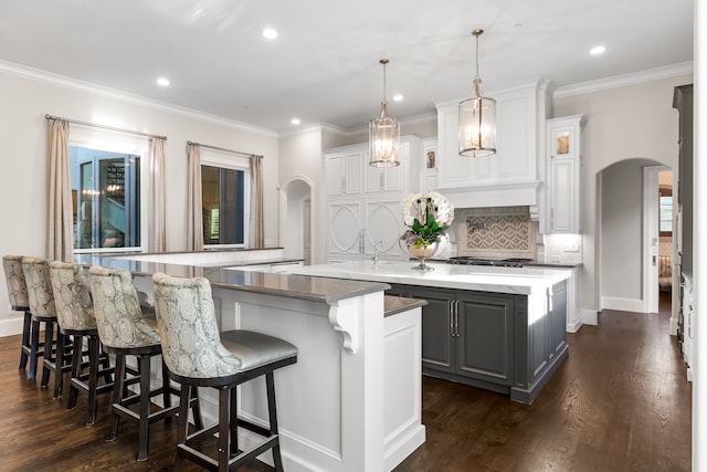 kitchen featuring recessed lighting, a large island, decorative backsplash, gray cabinets, and arched walkways