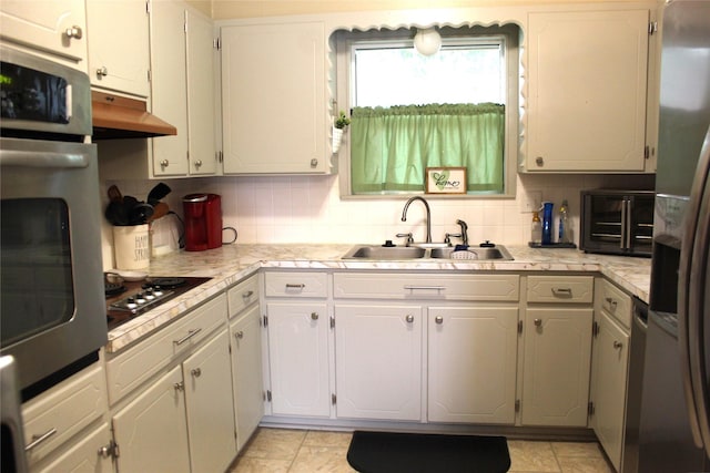 kitchen with light countertops, a sink, stainless steel appliances, and under cabinet range hood