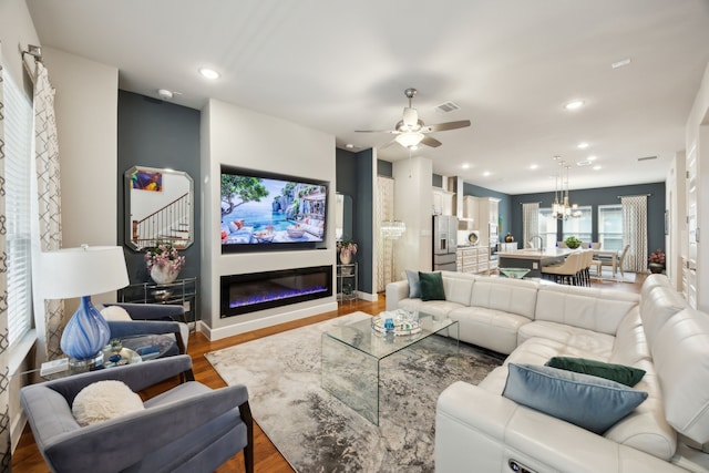 8218 Laflin Ln, Dallas, TX 75231 - living room featuring visible vents, wood finished floors, ceiling fan with notable chandelier, a glass covered fireplace, and recessed lighting