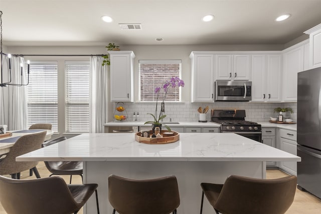 kitchen with visible vents, white cabinetry, appliances with stainless steel finishes, and a kitchen bar