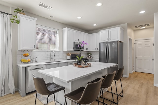 kitchen featuring a sink, a breakfast bar, stainless steel appliances, and visible vents