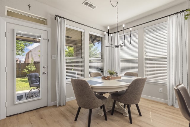 dining space with baseboards, visible vents, light wood finished floors, and a chandelier