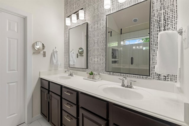 bathroom with a sink, baseboards, a stall shower, and double vanity