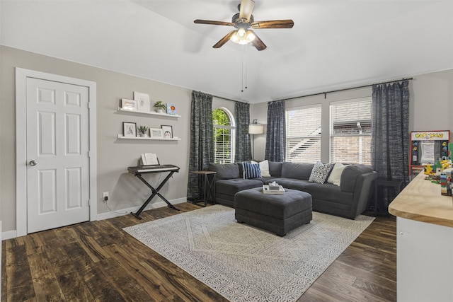 living area with dark wood-type flooring, a ceiling fan, and baseboards