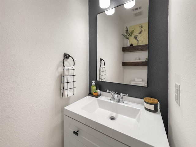 bathroom featuring a textured wall, visible vents, and vanity