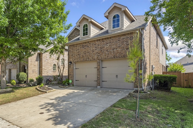 view of front of house with fence, concrete driveway, a front yard, and brick siding