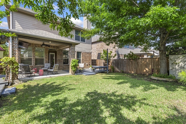 rear view of property featuring a ceiling fan, brick siding, fence, a yard, and a patio