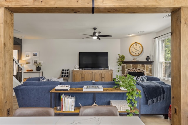 living room with ceiling fan, a fireplace, wood finished floors, visible vents, and stairway