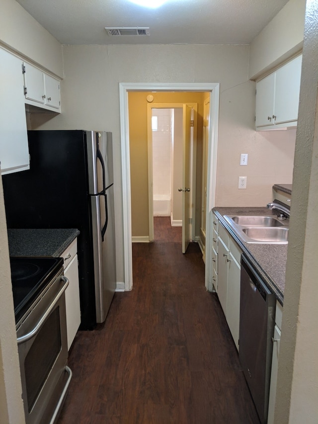 kitchen with white cabinetry, a sink, appliances with stainless steel finishes, visible vents, and dark wood-style floors