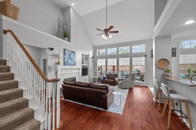 living area featuring recessed lighting, a tiled fireplace, high vaulted ceiling, ceiling fan, and wood finished floors