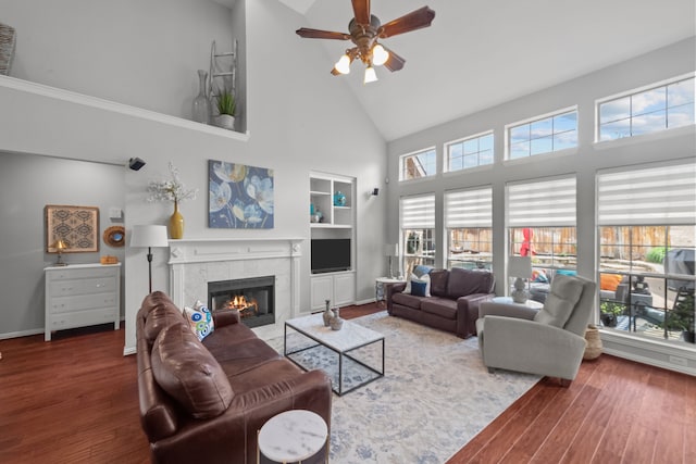 living room featuring a fireplace, wood finished floors, a healthy amount of sunlight, and high vaulted ceiling