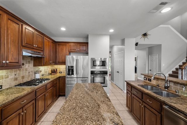 kitchen with decorative backsplash, under cabinet range hood, appliances with stainless steel finishes, a sink, and visible vents