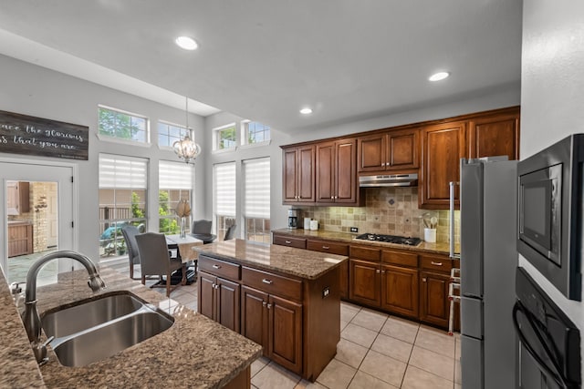 kitchen featuring freestanding refrigerator, under cabinet range hood, a kitchen island, black oven, and a sink