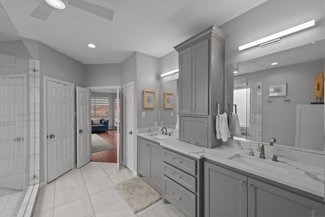 ensuite bathroom with double vanity, a sink, a shower stall, and a ceiling fan