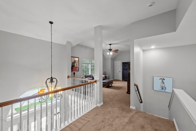 corridor featuring an inviting chandelier, carpet floors, vaulted ceiling, an upstairs landing, and baseboards