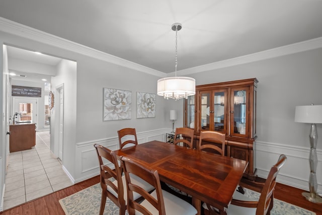 dining area featuring light wood-type flooring, wainscoting, and crown molding
