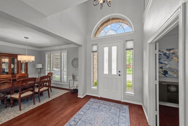 foyer entrance featuring a wealth of natural light, a notable chandelier, and dark wood-type flooring