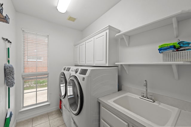 laundry room featuring a sink, visible vents, light tile patterned flooring, washer and dryer, and cabinet space