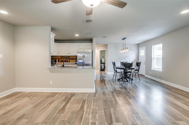kitchen featuring a sink, visible vents, light wood-type flooring, and stainless steel fridge with ice dispenser