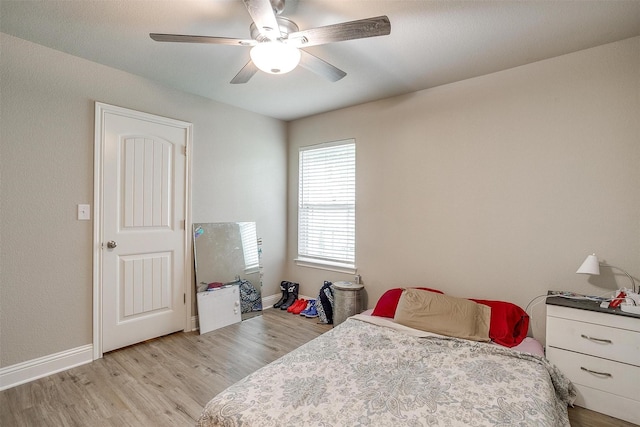 bedroom with a ceiling fan, baseboards, and light wood-style floors