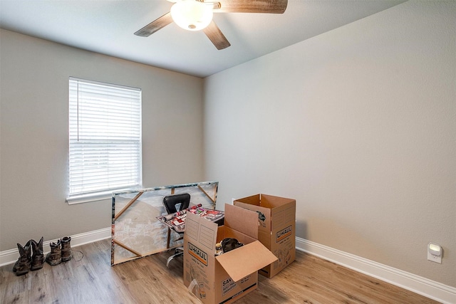 misc room with wood finished floors, a ceiling fan, and baseboards