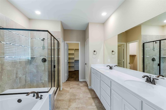 full bath featuring double vanity, a spacious closet, a shower stall, and a sink