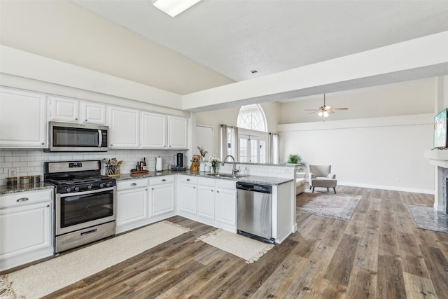 kitchen featuring a sink, white cabinetry, a peninsula, stainless steel appliances, and tasteful backsplash