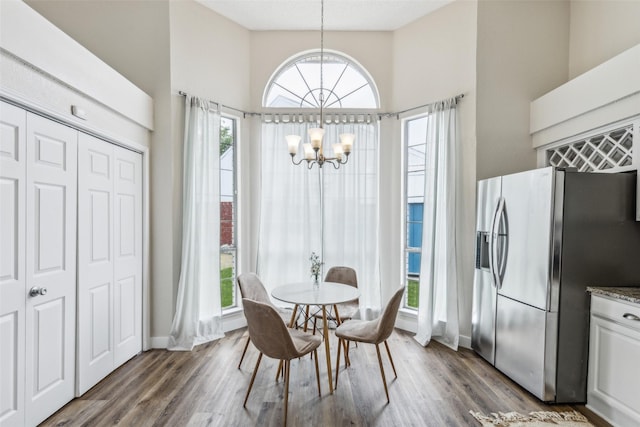 dining room featuring an inviting chandelier, dark wood-type flooring, baseboards, and a towering ceiling