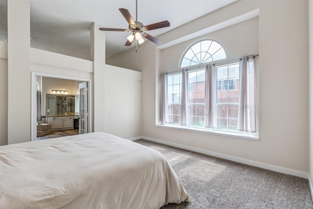 carpeted bedroom with vaulted ceiling, multiple windows, ensuite bathroom, and baseboards