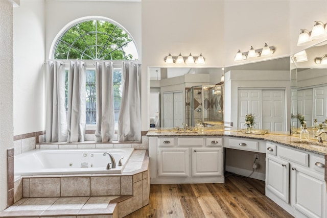 full bathroom with vanity, a jetted tub, a shower stall, and a towering ceiling