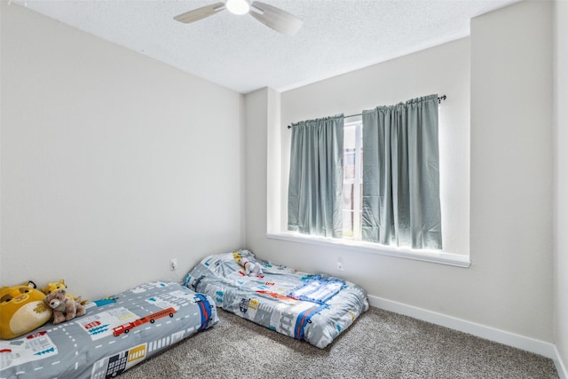 bedroom featuring carpet flooring, a textured ceiling, baseboards, and ceiling fan