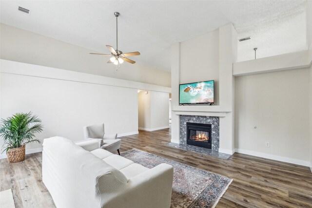 living area with visible vents, a fireplace, ceiling fan, and wood finished floors