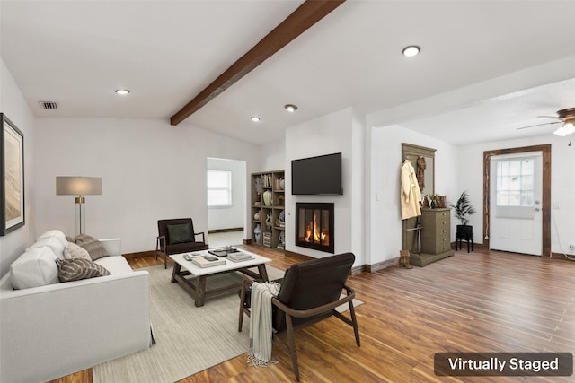 living room featuring visible vents, a glass covered fireplace, wood finished floors, and a healthy amount of sunlight