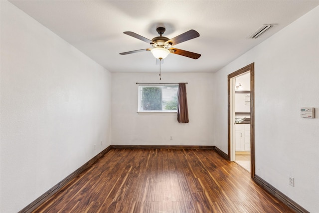 spare room with visible vents, a ceiling fan, dark wood-style flooring, and baseboards