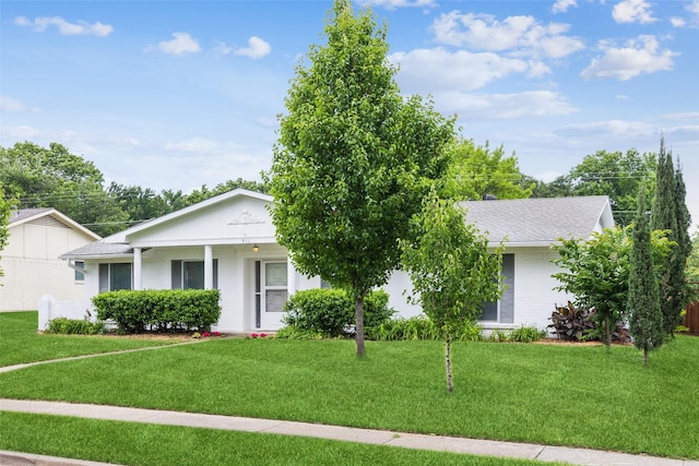 view of front of property with brick siding, a front lawn, and roof with shingles