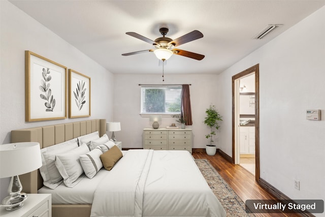 bedroom with ensuite bath, a ceiling fan, baseboards, wood finished floors, and visible vents