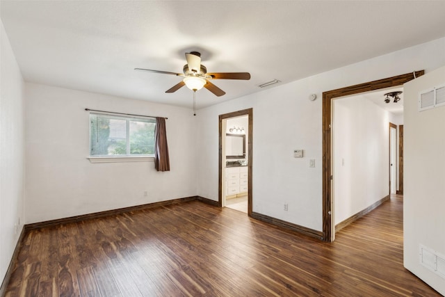 spare room featuring dark wood-style flooring, ceiling fan, visible vents, and baseboards