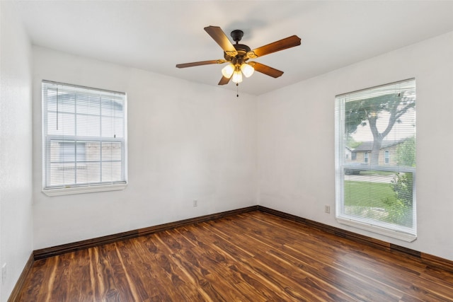 unfurnished room with baseboards, plenty of natural light, a ceiling fan, and dark wood finished floors