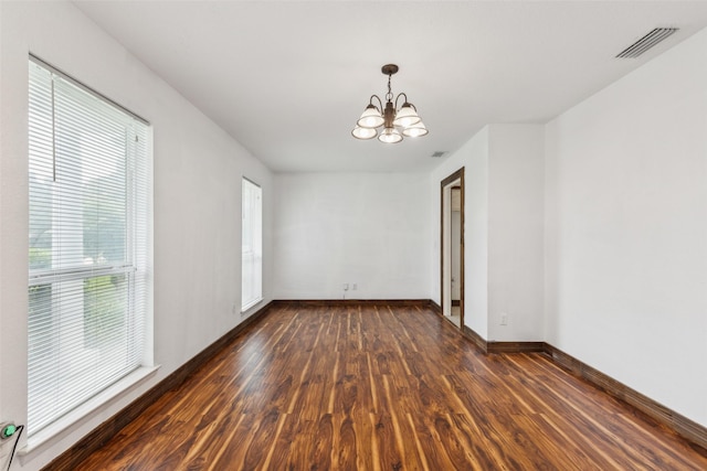unfurnished room with visible vents, dark wood-style flooring, baseboards, and a chandelier