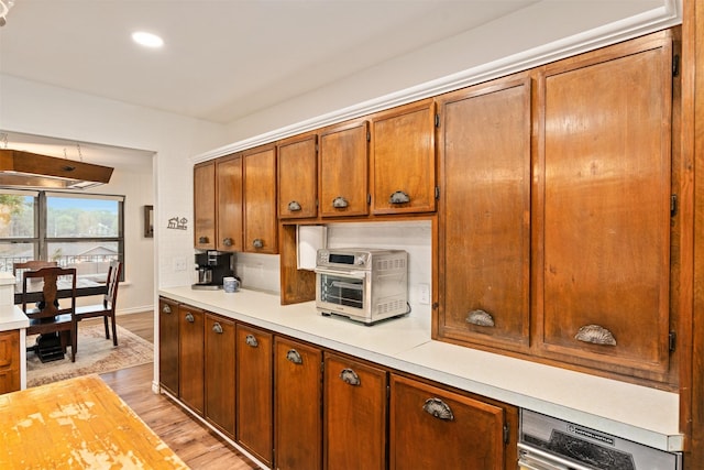 kitchen with a toaster, brown cabinets, light wood-style flooring, and light countertops